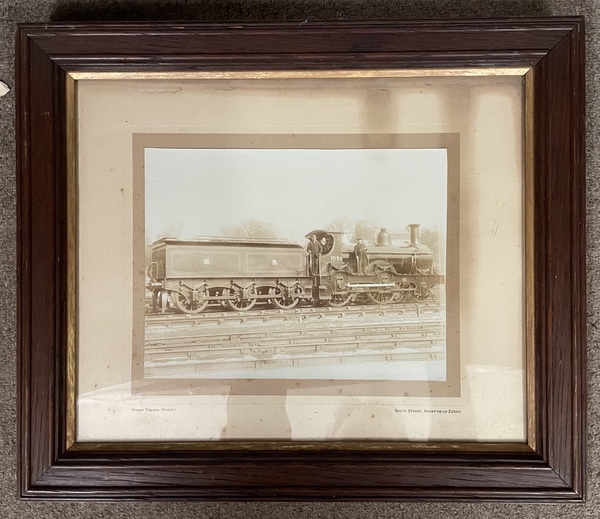 Framed and glazed photograph of Midland Railway 2-4-0 locomotive No.104A with its crew on the footplate posing in a small goods yard.