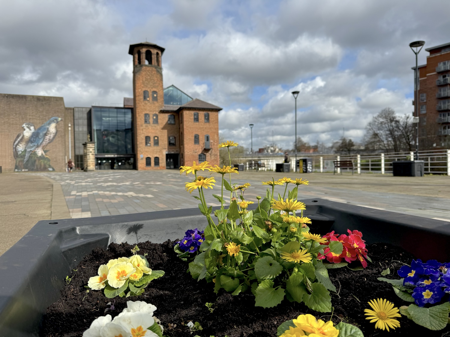 A view with the front of Derby's Silk Mill, home of the Museum of Making, in the background, gthe foreground composed of a colourful array of spring flowers.