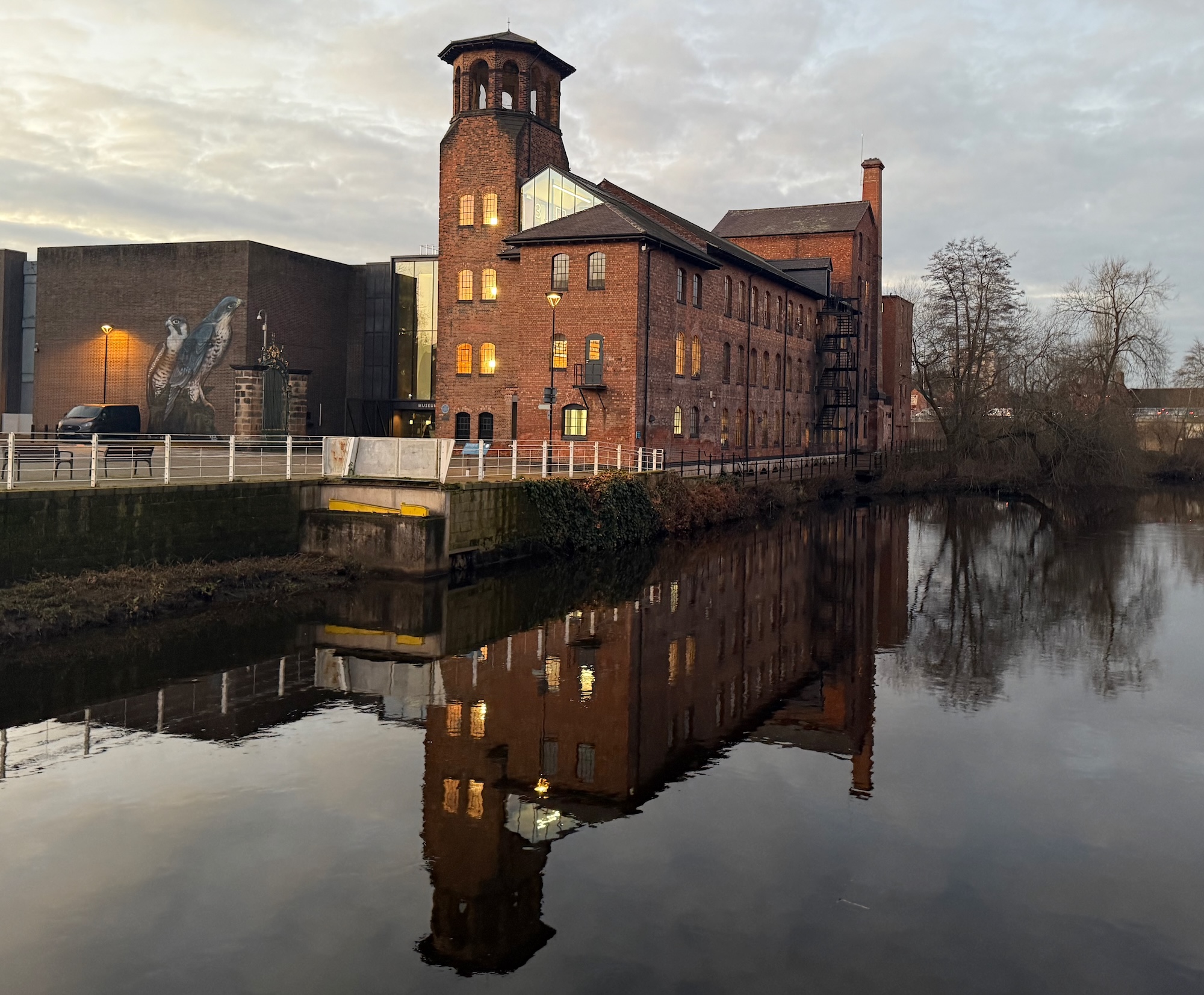 The Museum of Making in Derby's Silk Mill viewed from the footbridge across the River Derwent as dusk in Janaury