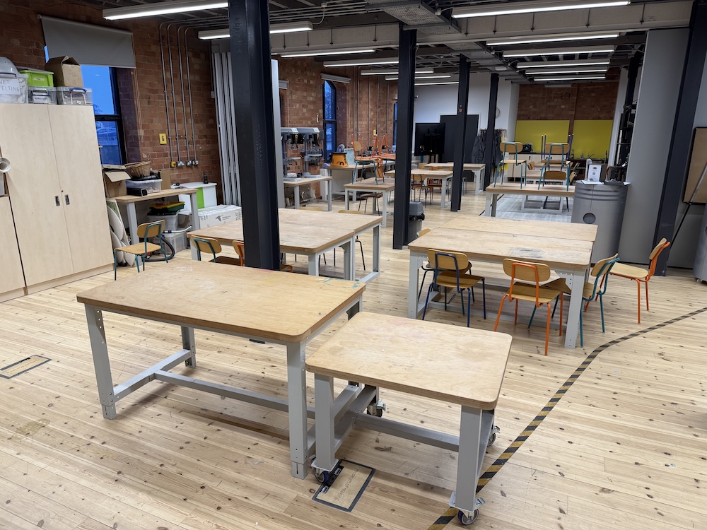 A view of the Studios where part of the Open Day is taking place. The view shows the long room with ten large tables with chairs where educational activities take place in the Museum of Making