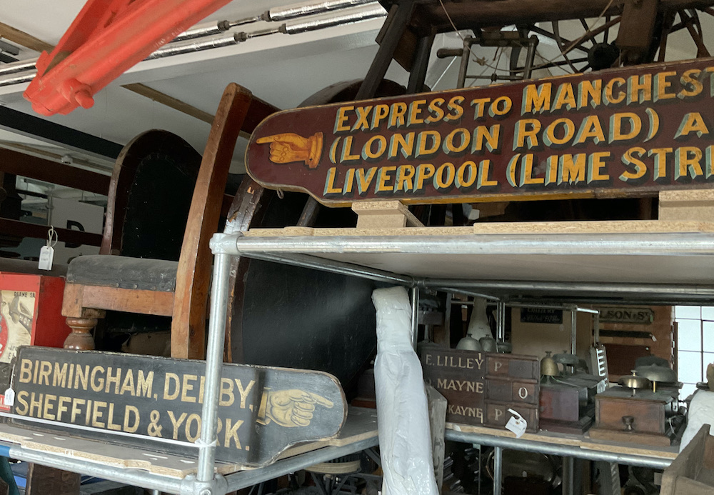 An ornately sign-written finger board pointing the way to the train to Birmingham, Derby, Sheffield and York and another, later example to the Express Train for Manchester and Liverpool